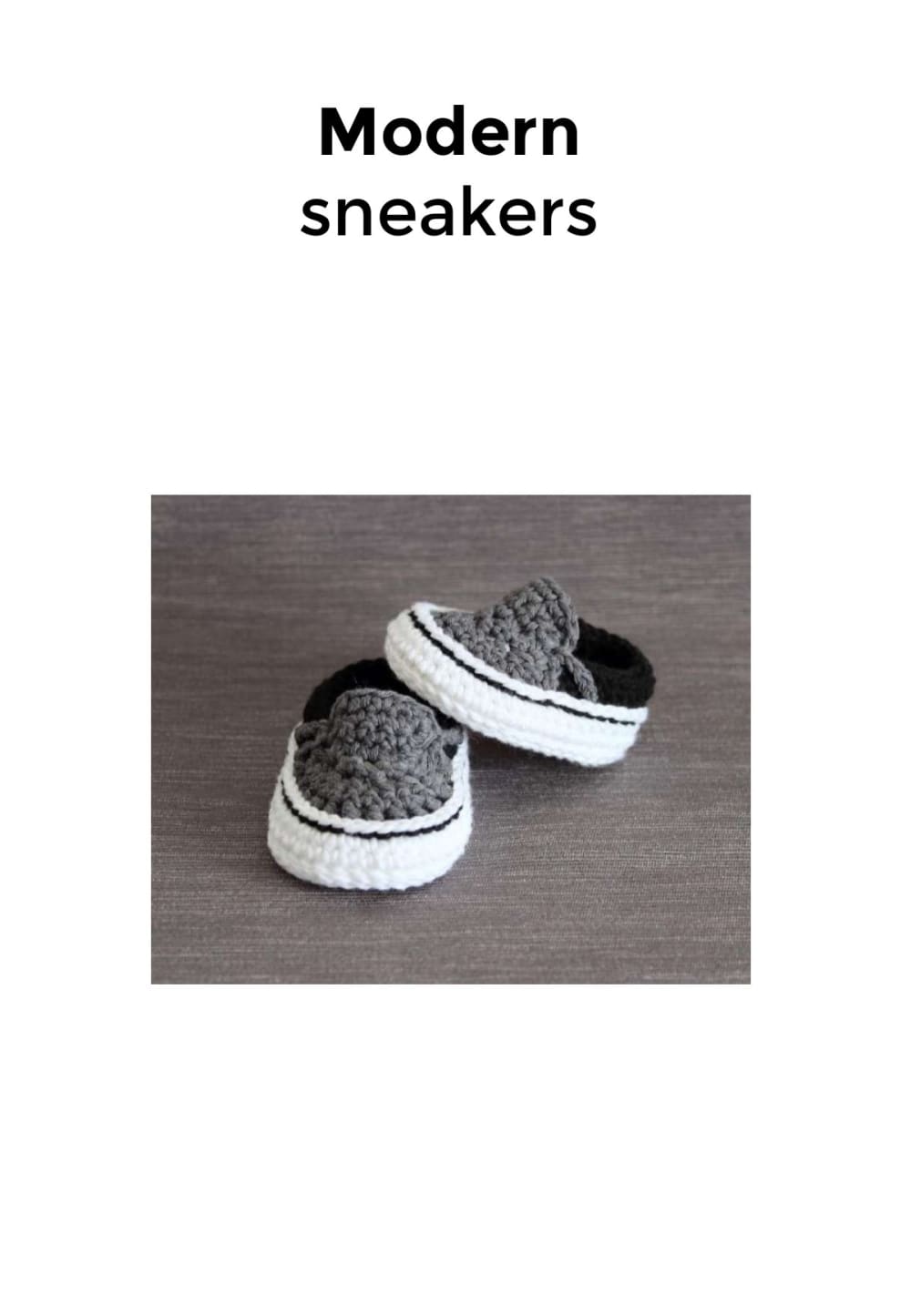 Grey and white crochet baby sneakers with a black stripe on a plain background
