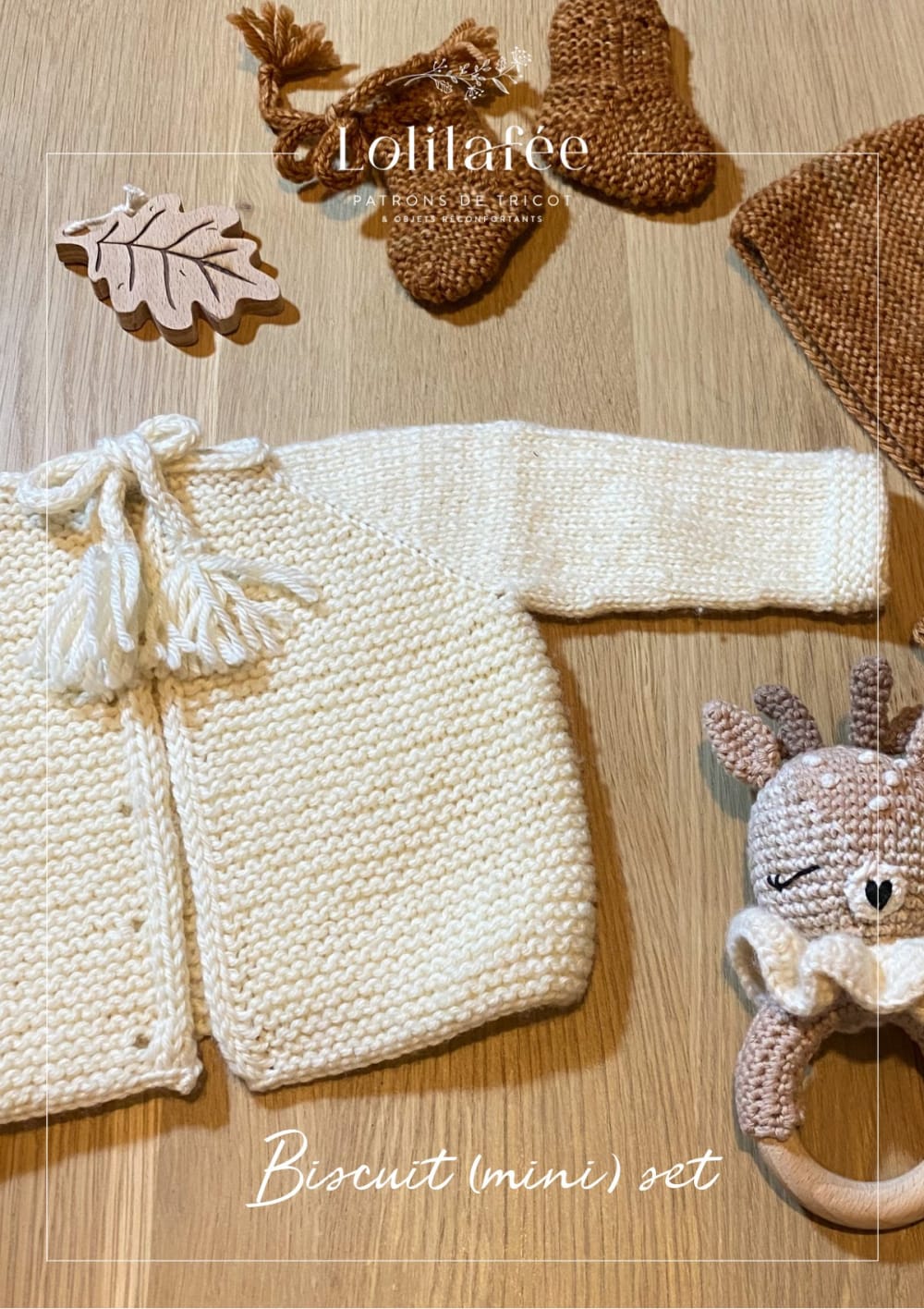 Cream garter stitch baby cardigan with tassel ties, brown booties and a bonnet laid on a wooden table