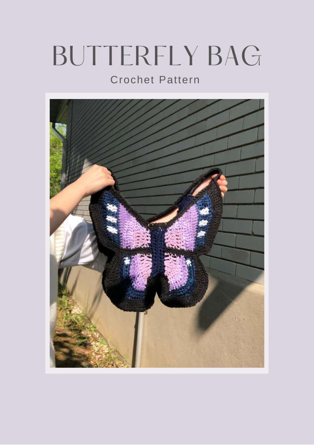 Black, purple and lilac crochet butterfly bag held up against a wall
