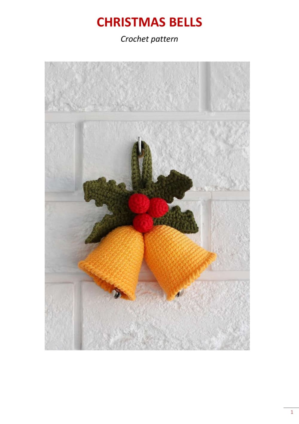 Two golden crochet Christmas bells with holly leaves, red berries and a loop for hanging on a white wall
