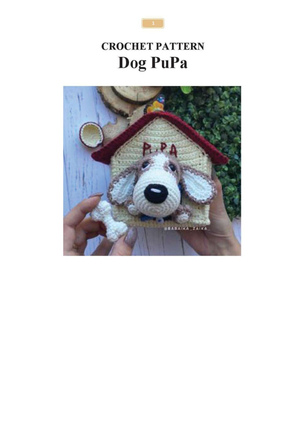 Crochet dog with floppy brown ears and a black nose looking out of a small red and yellow doghouse