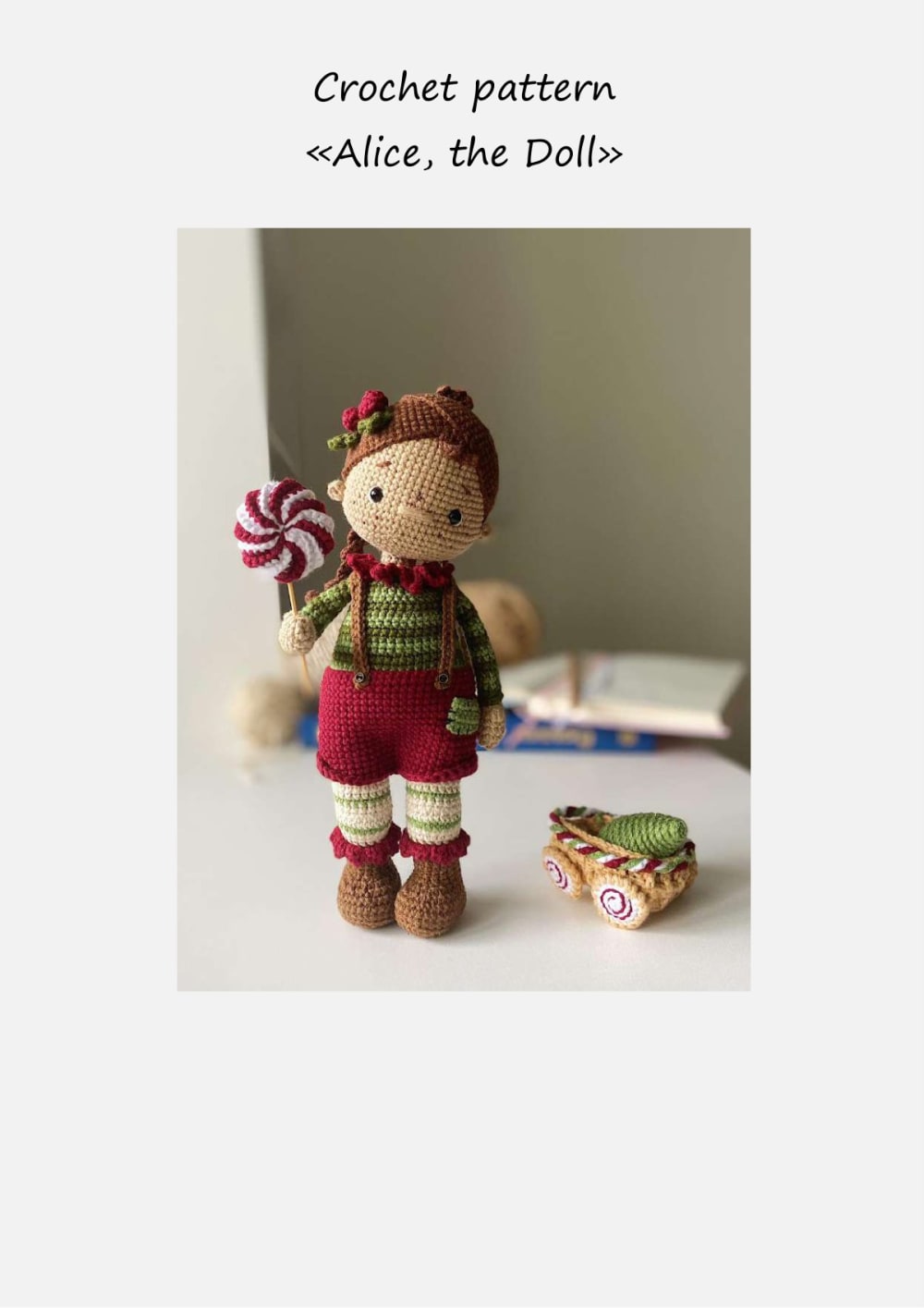 Amigurumi doll with brown braided hair, a green striped sweater, a red jumpsuit and a big peppermint lollipop