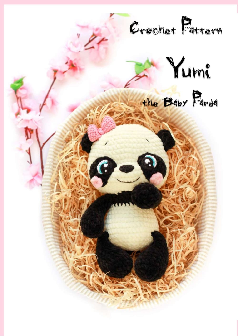 Plush crochet baby panda with big eyes and a pink bow sitting in a nest