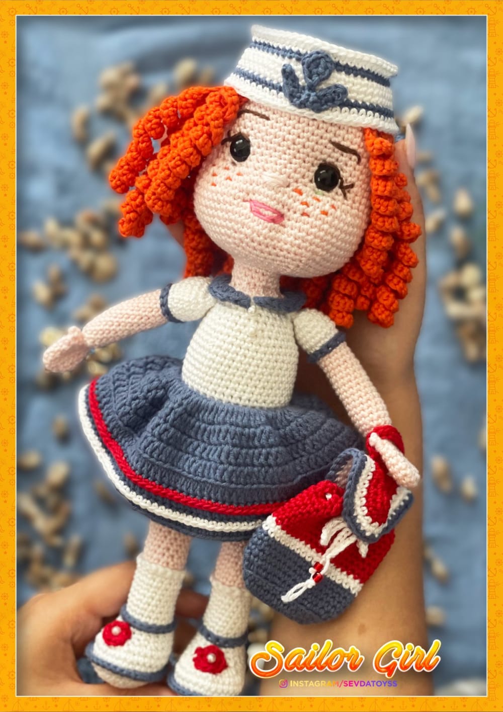 Crochet sailor girl doll with curly orange hair, a sailor hat and a blue striped skirt