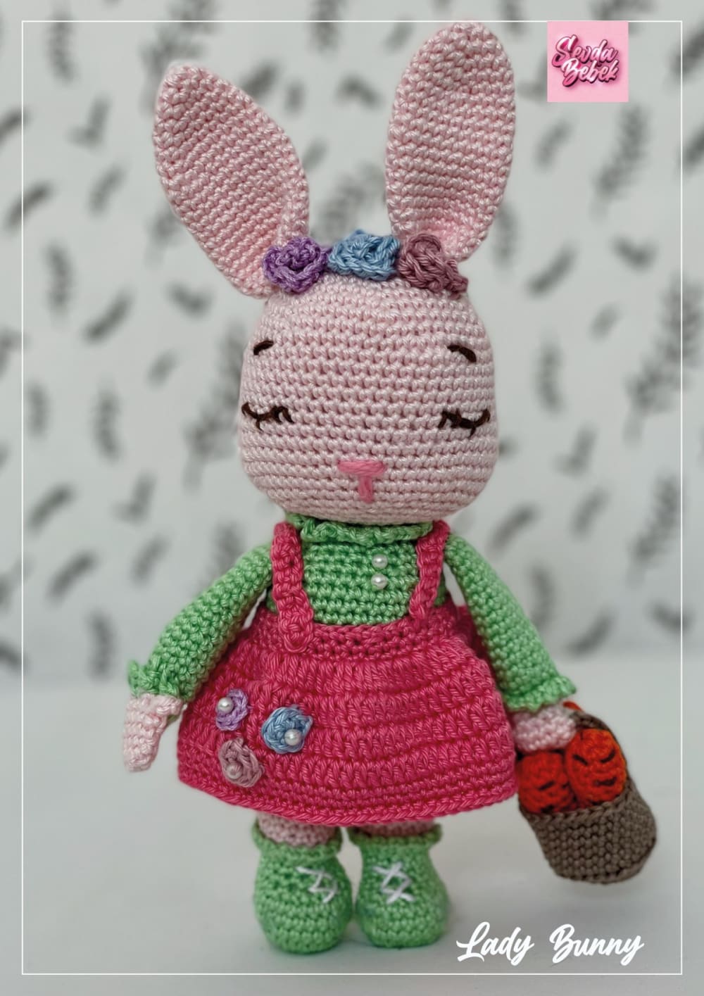 Pink crochet bunny in a dark pink dress and green top with flowers on her ears