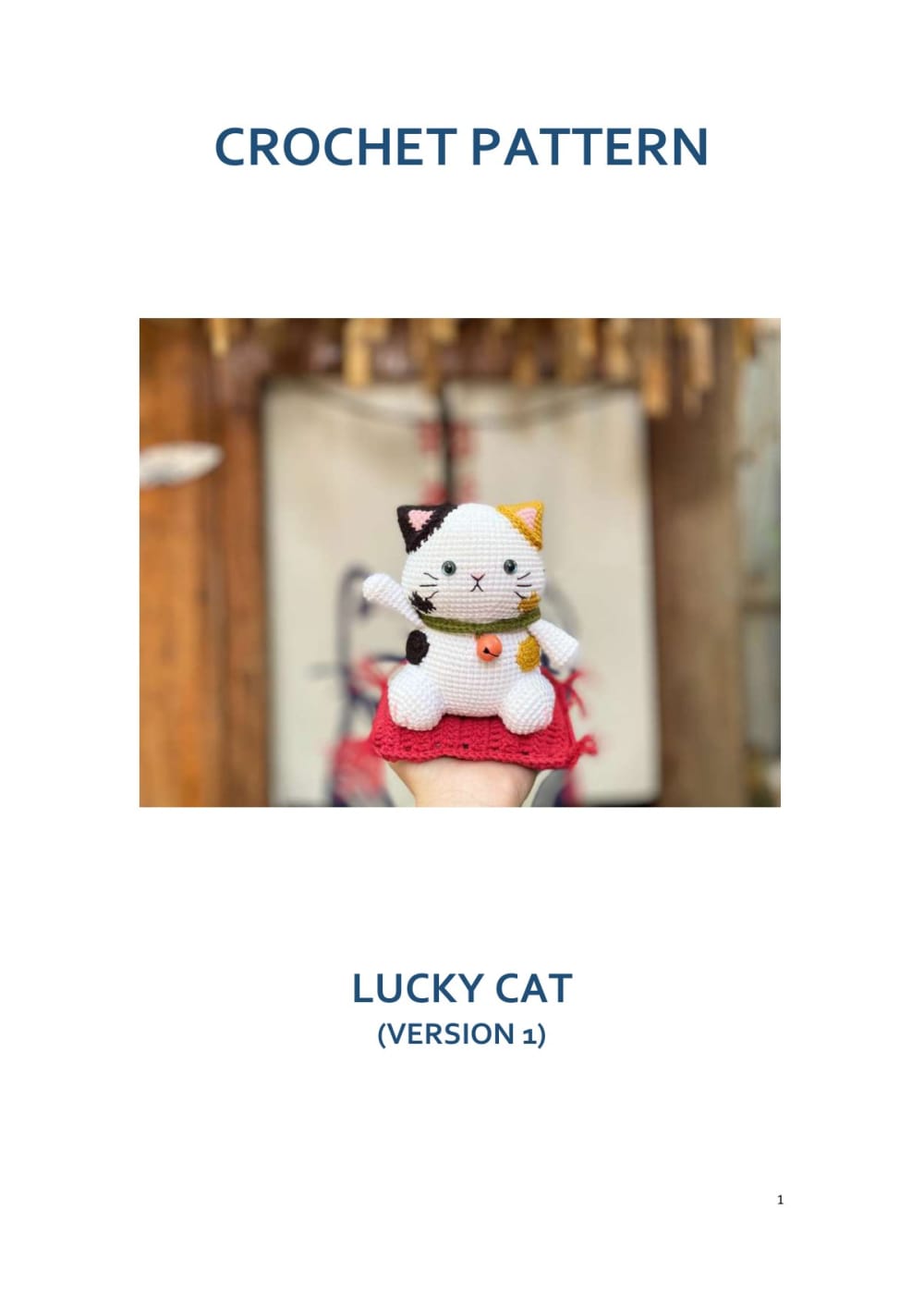 White lucky cat amigurumi with a red bib and a gold bell