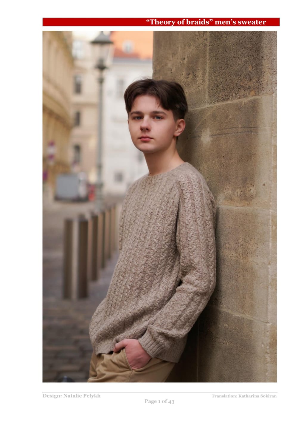 Man wearing a beige cable knit sweater leaning on a wall