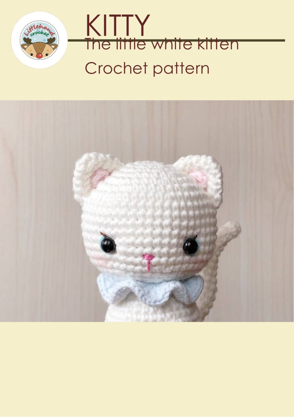 Small white crochet kitten with a light blue bow and pink cheeks
