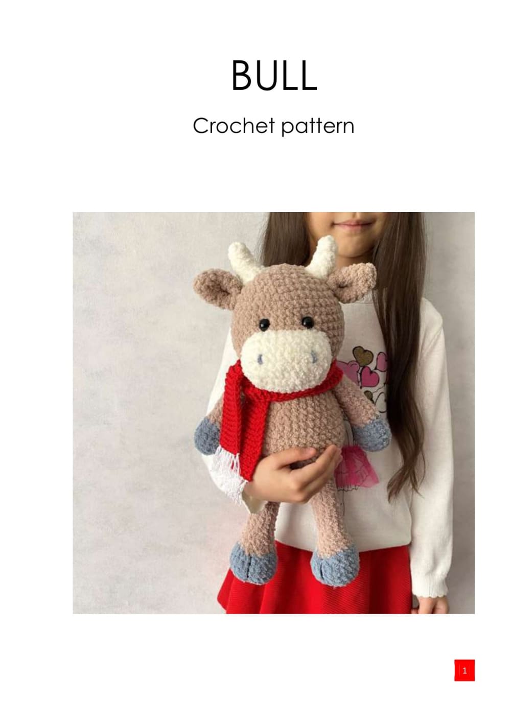 Beige crochet bull with a red scarf held in arms