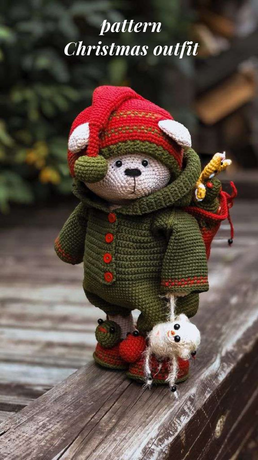 Teddy bear in a green and red crochet Christmas outfit with a gift bag