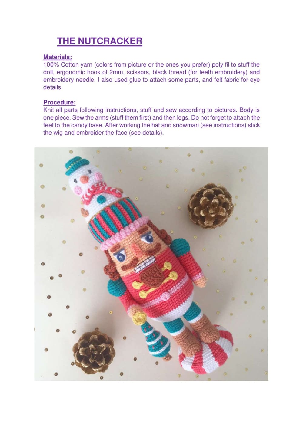 Crochet nutcracker doll in red and pink standing next to pine cones