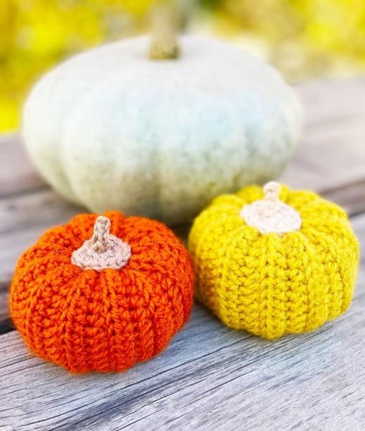 Crochet pumpkin amigurumi pattern: finished orange and yellow crochet pumpkins on a wooden table