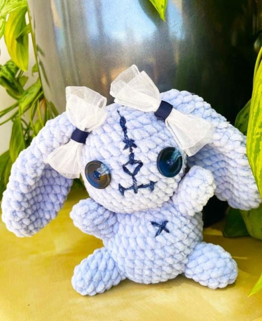 Zombie bunny crochet pattern: finished lilac amigurumi zombie bunny with white bows, button eyes and stitched details