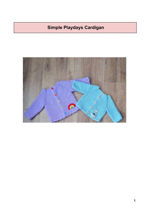 Lilac and turquoise crochet baby cardigans with a rainbow applique on a wooden floor
