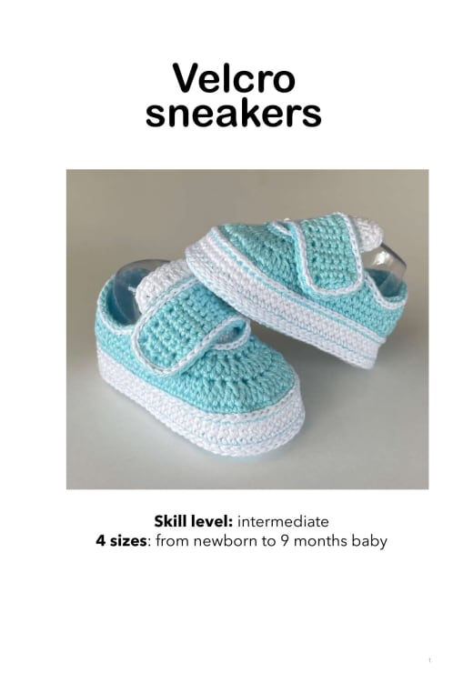 Turquoise and white crochet baby sneakers with a velcro strap, shown on a light background