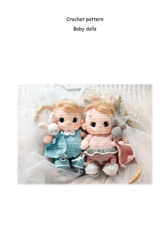 Two crochet baby dolls with blond hair dressed in teal and pink outfits among flowers