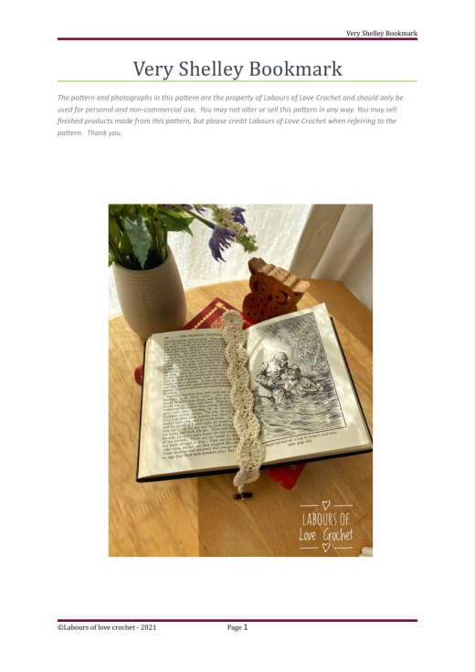 Cream crochet shell bookmark lying on an open vintage book beside a vase of flowers