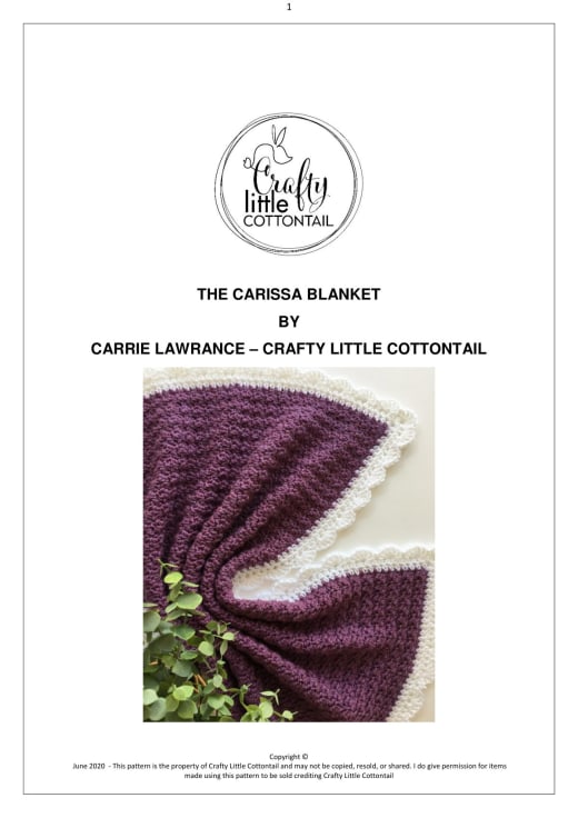 Plum purple chunky crochet baby blanket with a white scalloped border lying next to green leaves