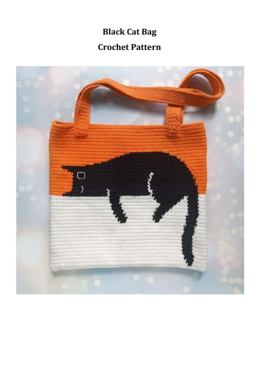 Orange and white crochet tote bag with a black cat lying across the top and a hanging tail