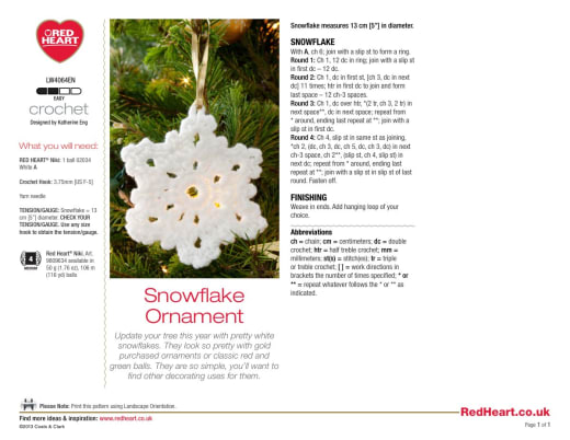 White crochet snowflake ornament with six points hanging on a Christmas tree