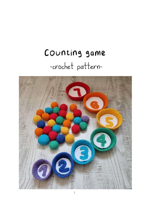Crochet counting game with colored bowls, many small balls and white circles with numbers