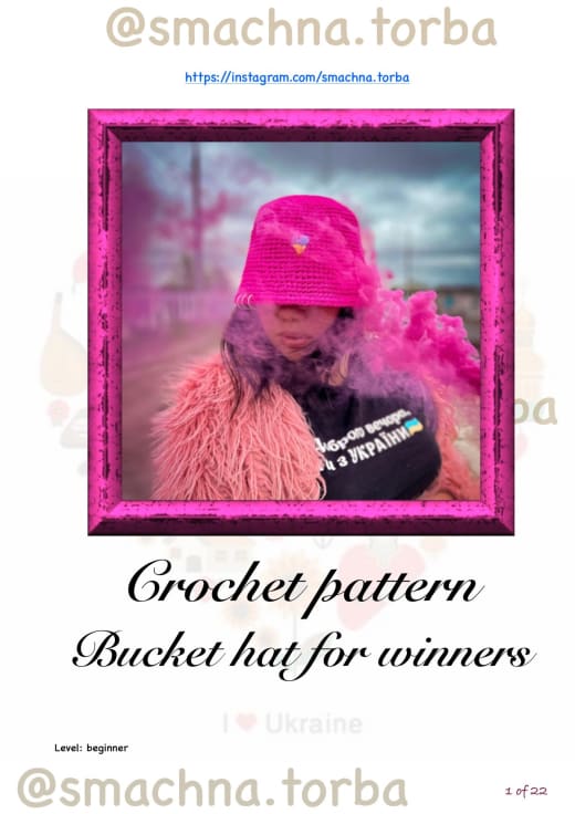 Bright pink crochet raffia bucket hat with a shiny finish and a small charm on the front