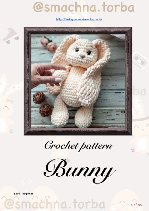 Peach plush crochet bunny with long floppy ears sitting in a wooden frame
