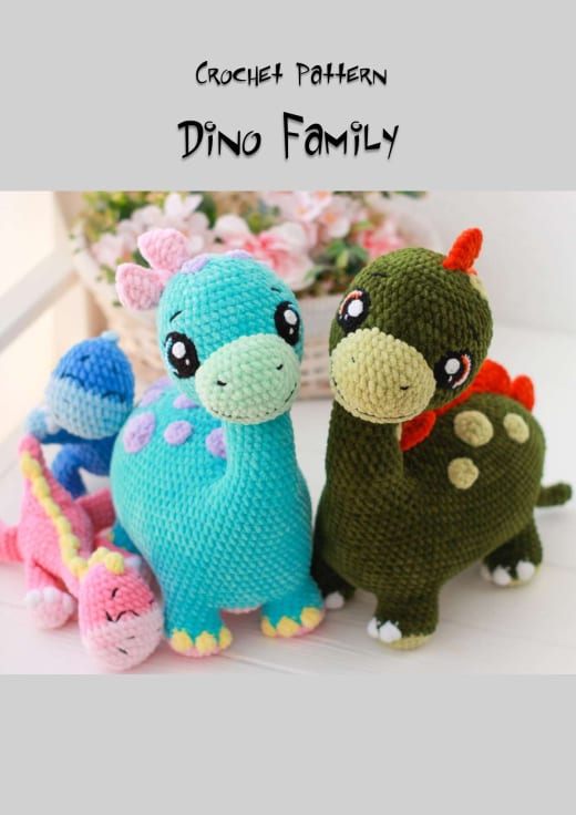 Three plush crochet dinosaurs in turquoise, dark green and a small blue one with a pink one on the left