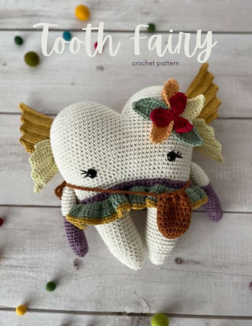 Crochet tooth fairy toy with golden wings, a flower crown and a striped skirt