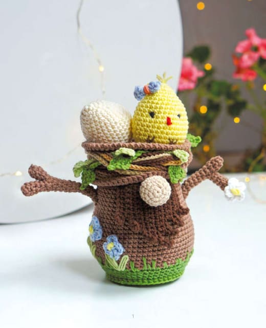 Crochet tree stump gnome with branches, a green nest and a yellow chick on top
