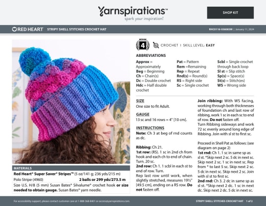 Woman wearing a pink and blue striped shell stitch crochet hat with a pom pom