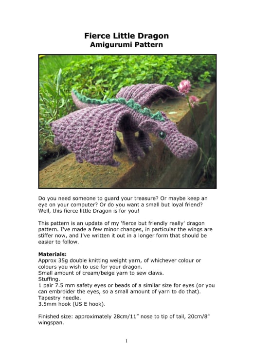 Purple crochet dragon with spread wings sitting on a mossy rock