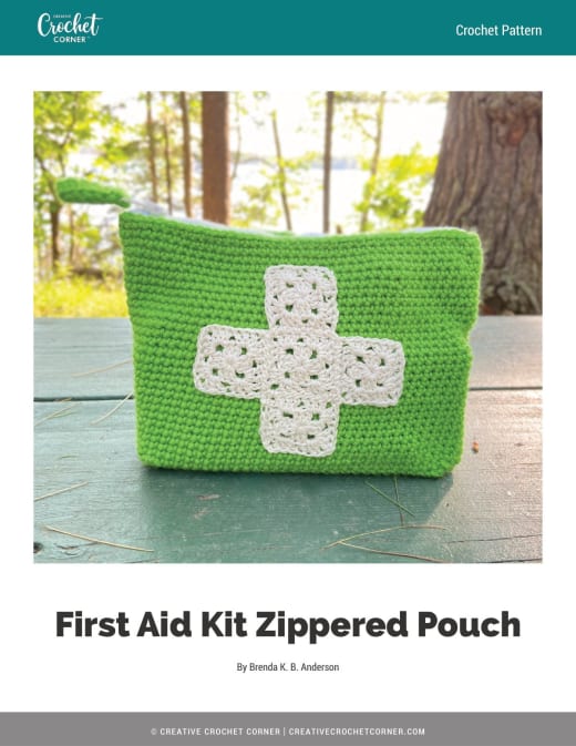 Green crochet zippered pouch with a cream granny square cross emblem