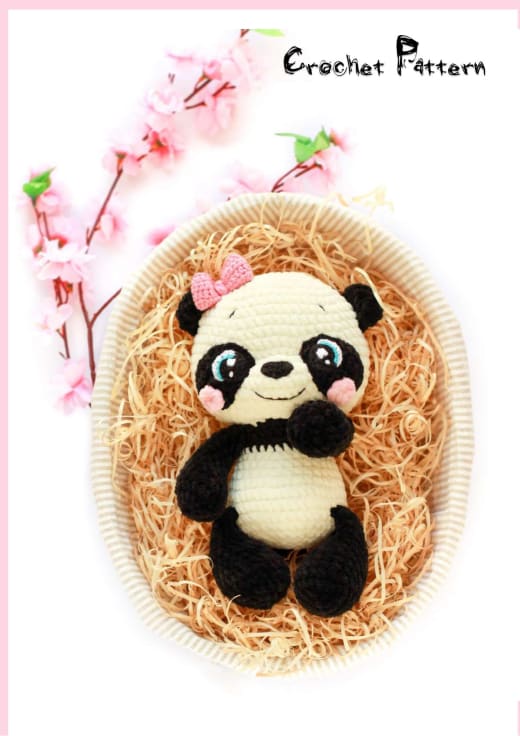 Plush crochet panda with big eyes sitting in a nest