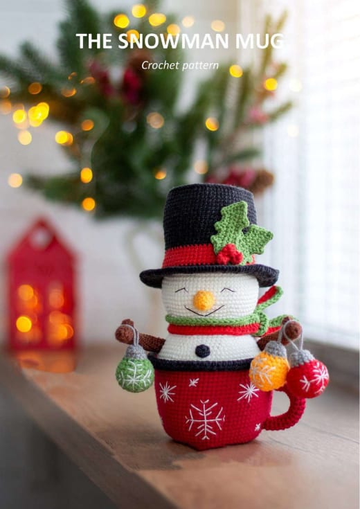 Snowman in a red Christmas mug with a black top hat and holly