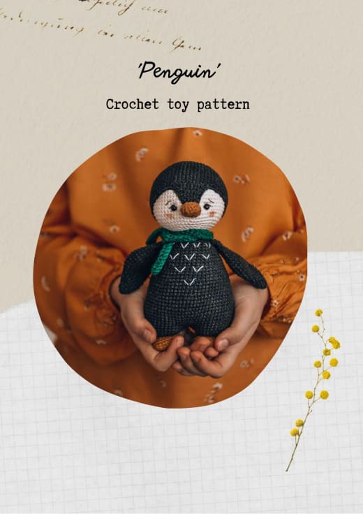 Black and cream crochet penguin with a scarf held in hands
