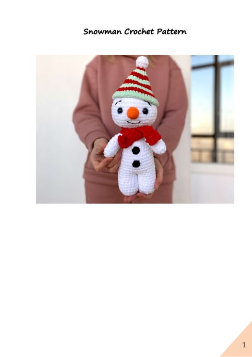 Plush white snowman with a red and green striped hat and scarf held in hands
