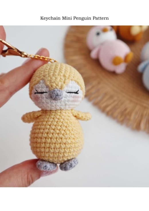 Yellow crochet mini penguin keychain held in hand