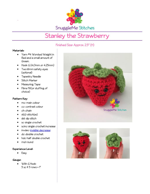 Smiling red crochet strawberries with green leafy tops held in a hand