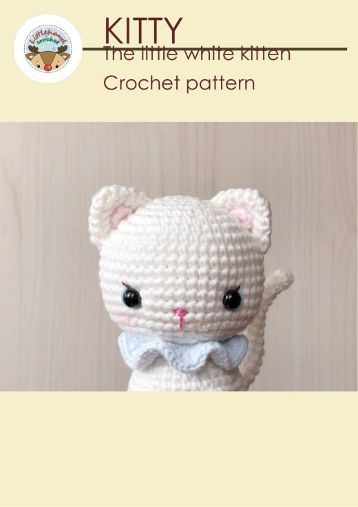 Small white crochet kitten with a light blue bow and pink cheeks