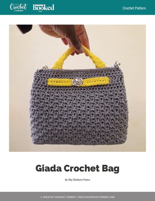 Grey crochet handbag with yellow handles and trim held up by hand