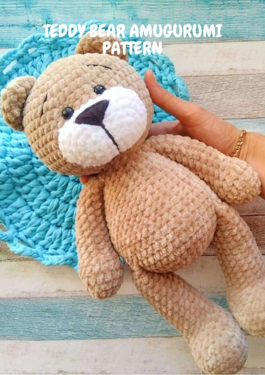 Plush brown teddy bear amigurumi lying on a blue blanket