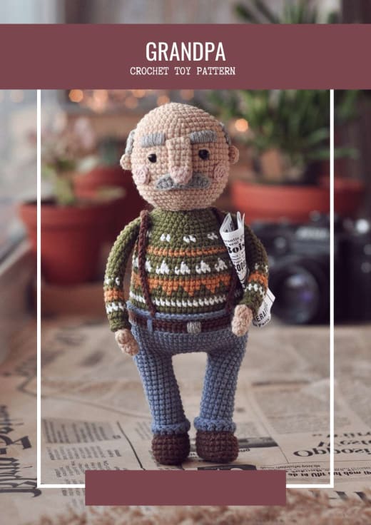 Crochet grandpa doll with grey hair, moustache, green patterned sweater and blue trousers