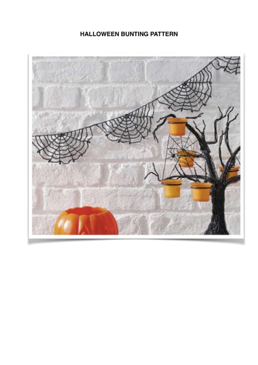 Black crochet spiderweb bunting hanging on a white brick wall