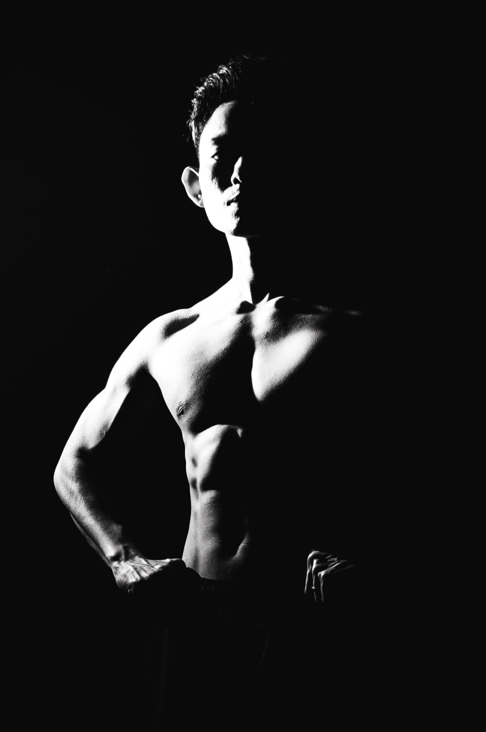Side-lit portrait, hand on hip, dramatic single-source light