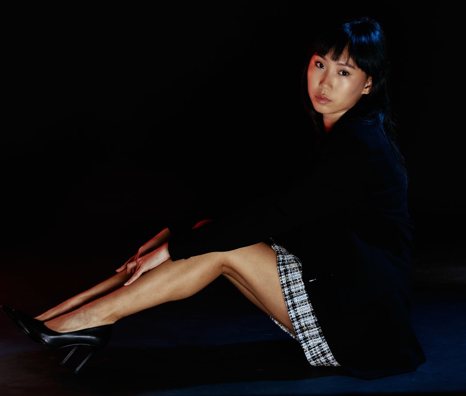Reclined portrait on a dark set, dramatic rim-lit legs