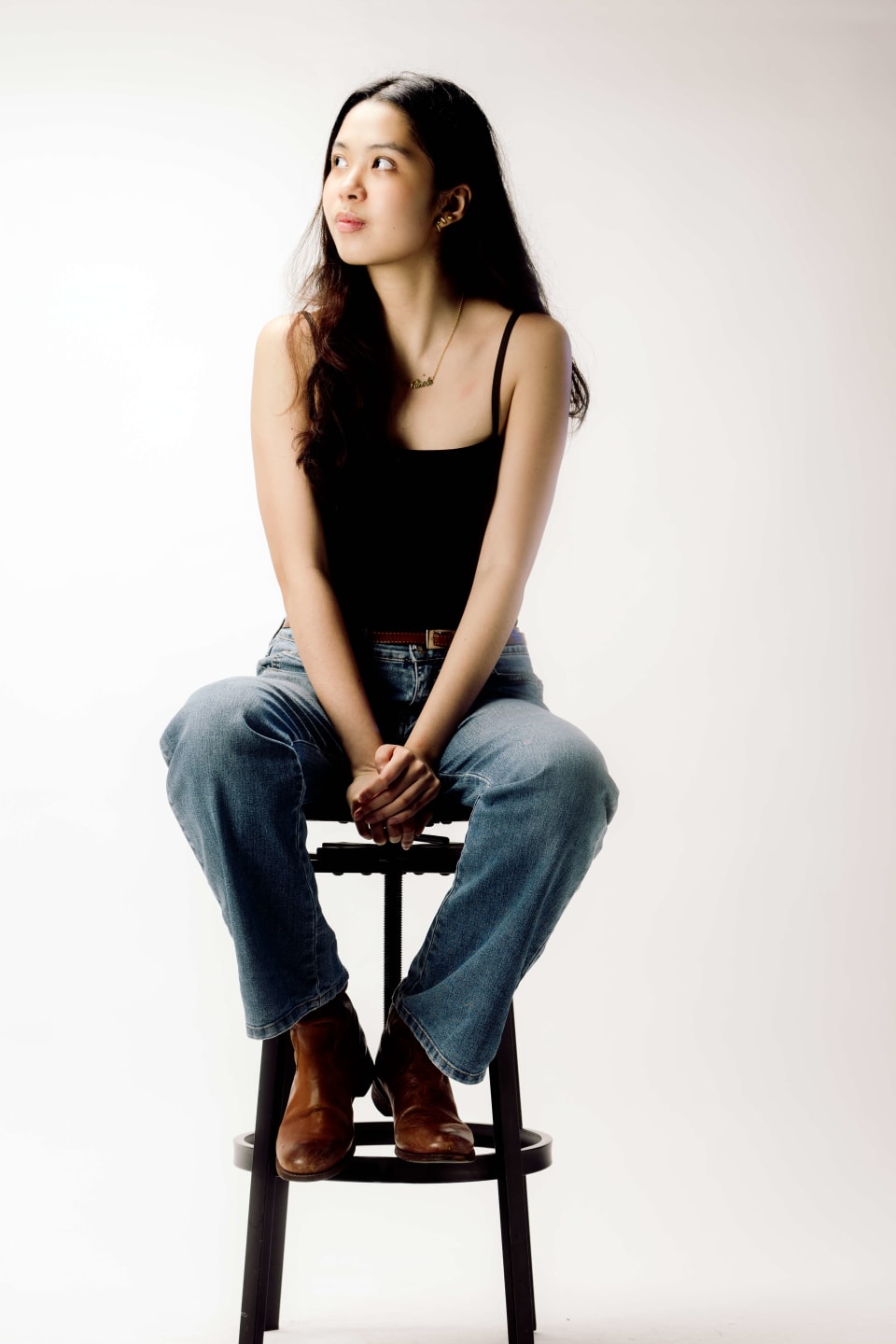 Seated portrait on a stool, hands clasped