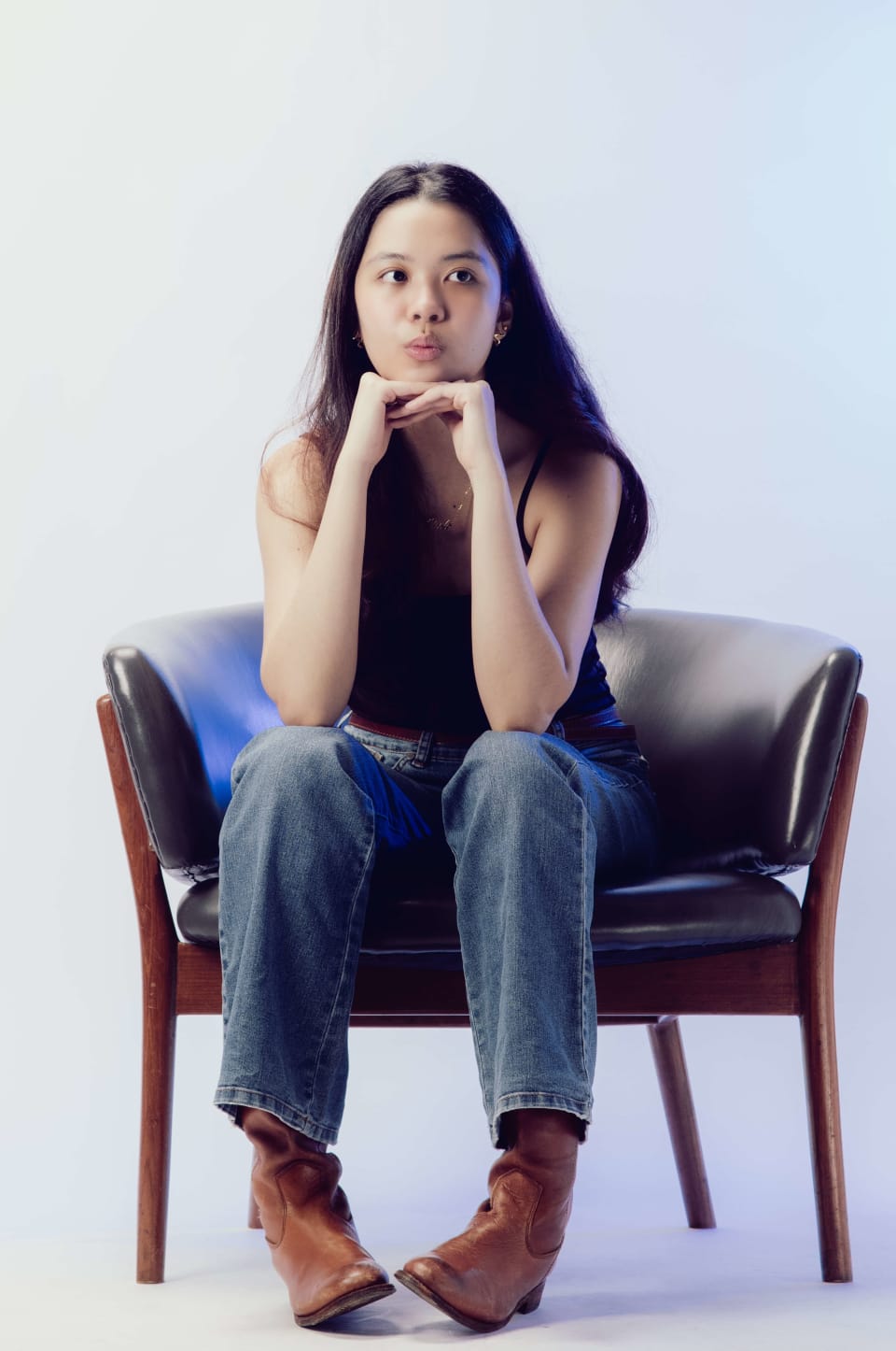 Seated portrait in a leather armchair, chin resting on hands