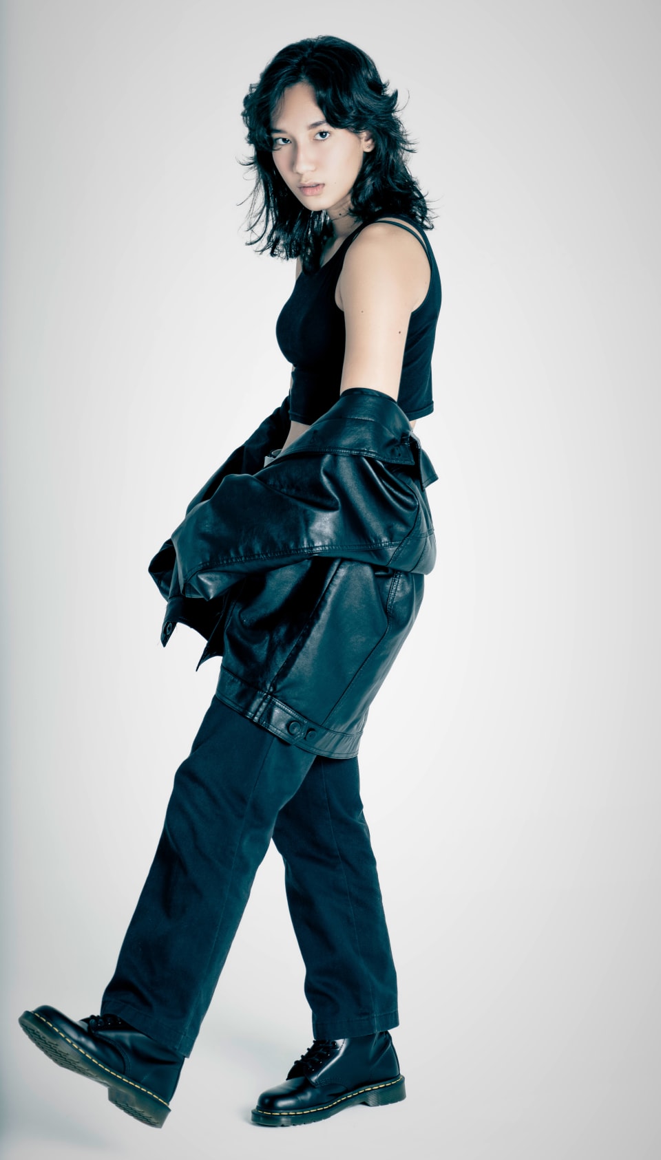 Fashion portrait, leather jacket draped over the shoulder, grey backdrop