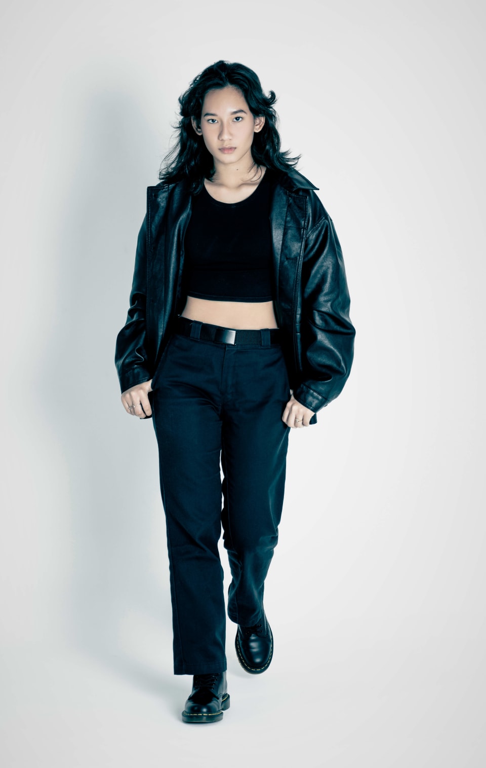 Fashion portrait, walking forward in a leather jacket, grey backdrop